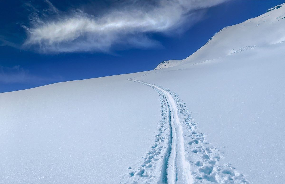 Piste de ski en poudre sur une montagne enneigée sous un ciel bleu avec nuages Piste de ski en poudre sur une montagne enneigée sous un ciel bleu avec nuages