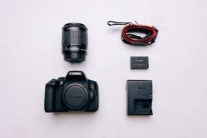 Un appareil photo Canon, objectif, batterie, chargeur et câble sur fond blanc