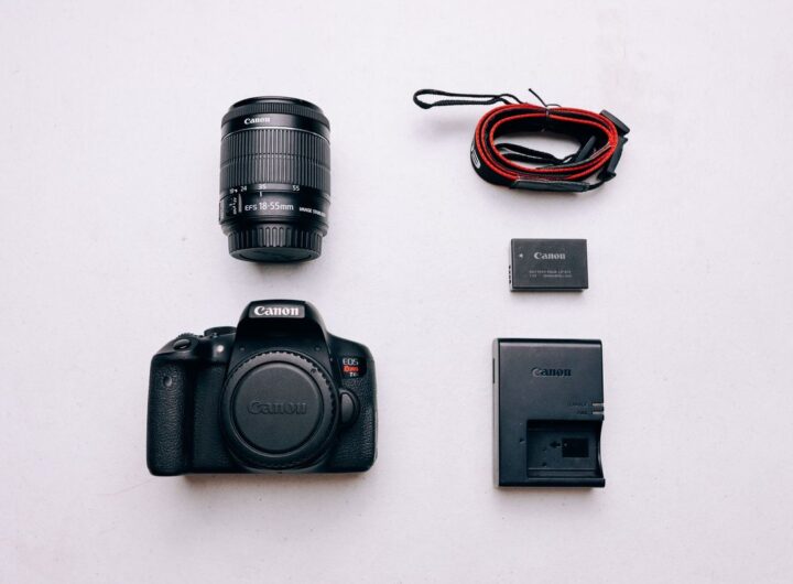 Un appareil photo Canon, objectif, batterie, chargeur et câble sur fond blanc