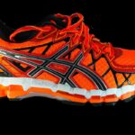 Chaussure de course orange et noire avec semelle blanche et noire