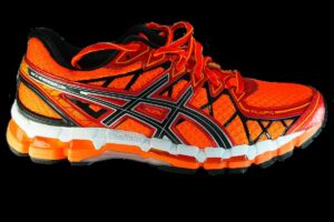 Chaussure de course orange et noire avec semelle blanche et noire