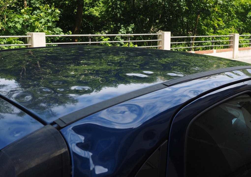 Voiture noire sur un pont au-dessus d'une rivière, entourée d'arbres