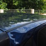 Voiture noire sur un pont au-dessus d'une rivière, entourée d'arbres