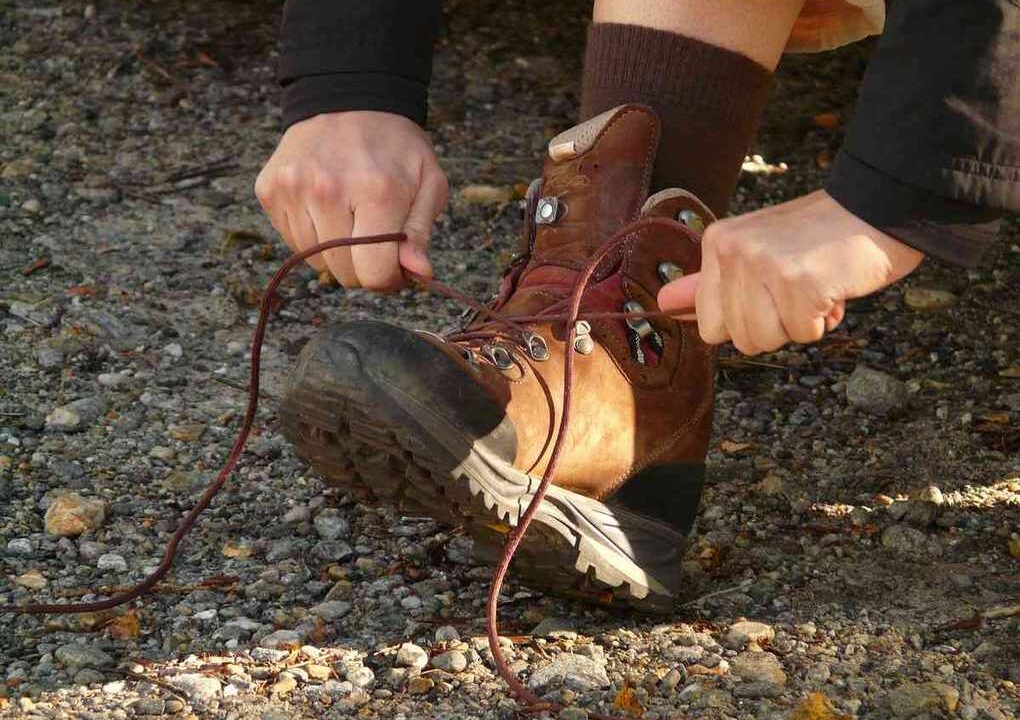 Person nouant lacets de bottes de randonnée sur un terrain rocheux