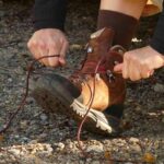 Person nouant lacets de bottes de randonnée sur un terrain rocheux