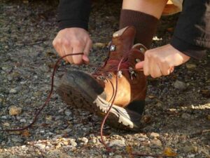 Person nouant lacets de bottes de randonnée sur un terrain rocheux