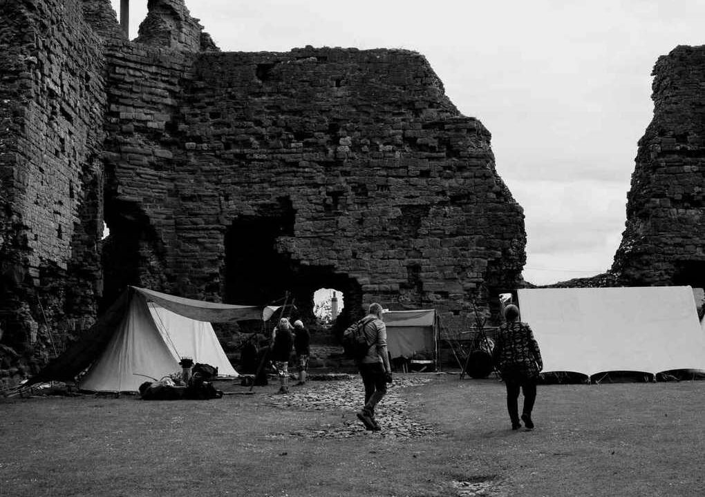 Tentes blanches dressées face aux ruines imposantes d'un château médiéval