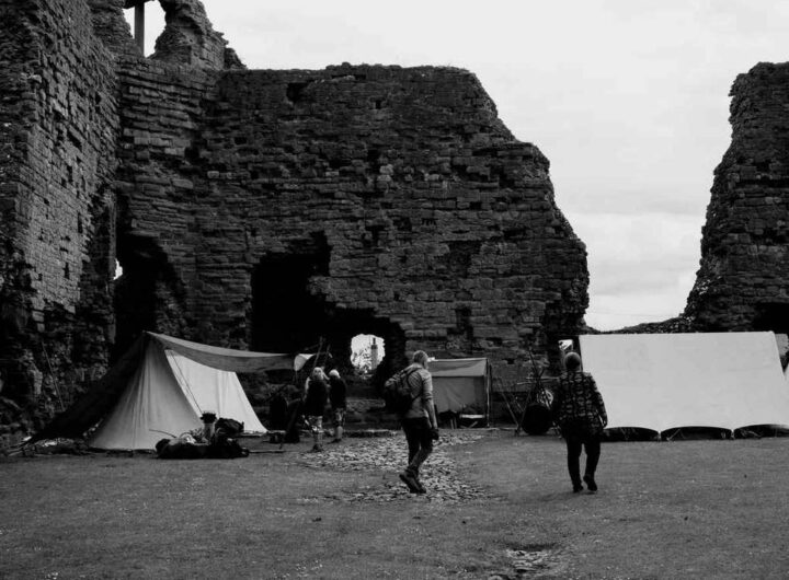 Tentes blanches dressées face aux ruines imposantes d'un château médiéval