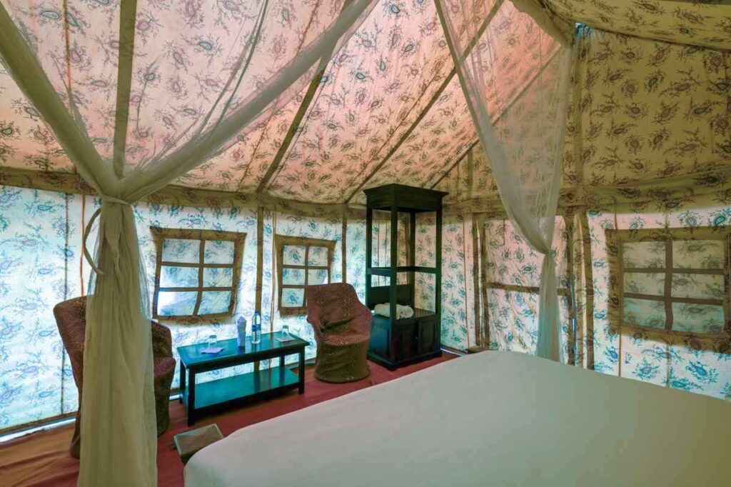 Intérieur de tente luxueuse avec lit, fauteuils, table et moustiquaire