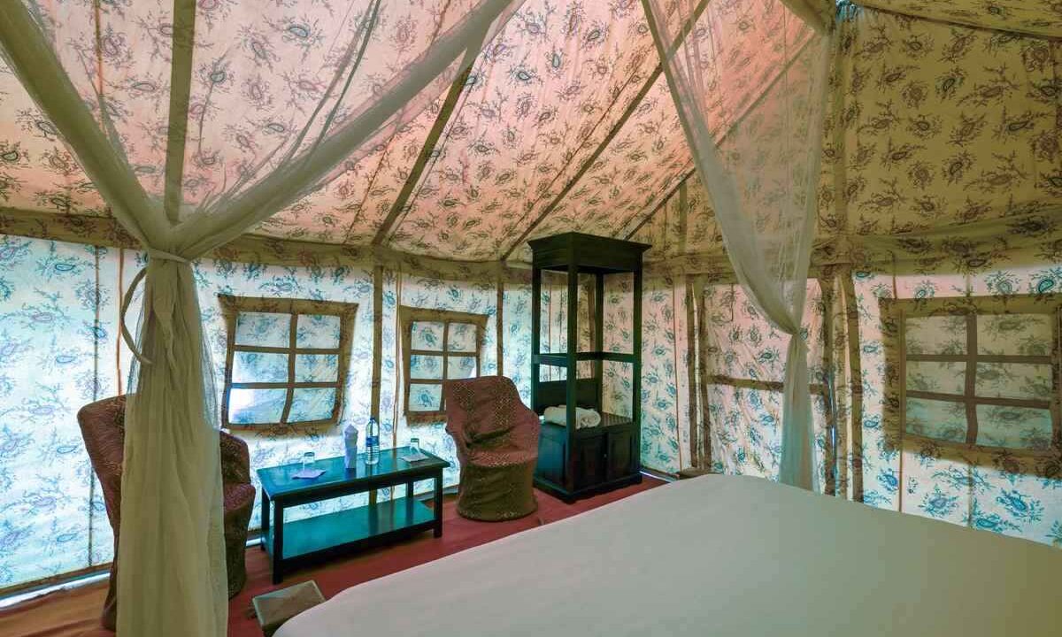 Intérieur de tente luxueuse avec lit, fauteuils, table et moustiquaire