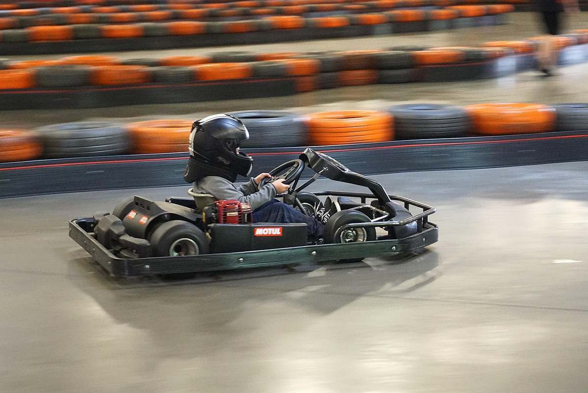 Un conducteur avec casque pilote un karting intérieur