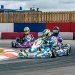 Trois karts dérapent en virage sur circuit, pilotes en casques colorés