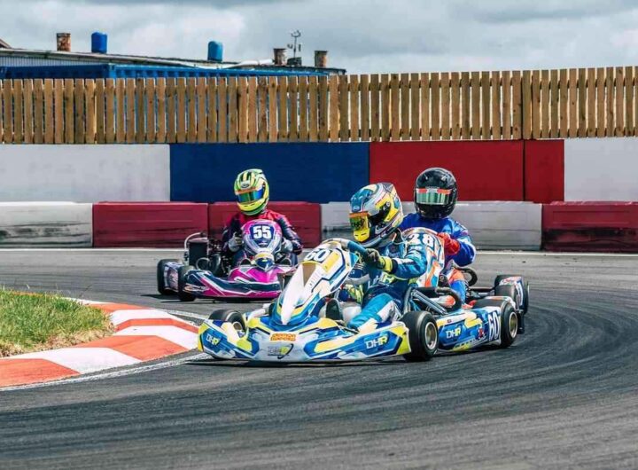 Trois karts dérapent en virage sur circuit, pilotes en casques colorés